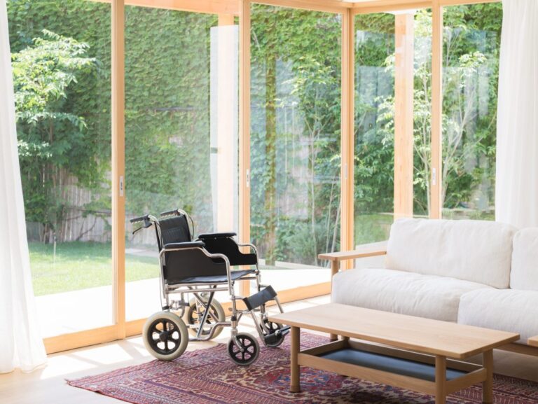 Leerer Rollstuhl in einem hellen Wohnzimmer – Pflege zu Hause oder im Pflegeheim?